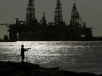 FILE - A man wears a face mark as he fishes near docked oil drilling platforms, Friday, May 8, 2020, in Port Aransas, Texas. FILE - A man wears a face mark as he fishes near docked oil drilling platforms, Friday, May 8, 2020, in Port Aransas, Texas.