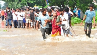 Young men help an elderly women wade through a waterlogged street in Nellore, Andhra Pradesh. (AP)