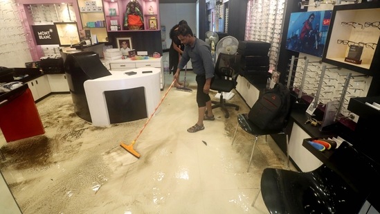 Shopkeepers sweep out the floodwater that entered the shop following heavy rainfall in Chennai, Tamil Nadu.(ANI)
