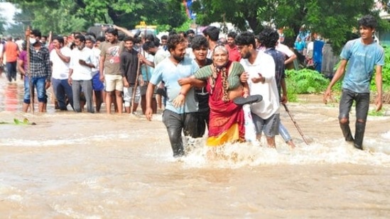 Young men help an elderly women wade through a waterlogged street in Nellore, Andhra Pradesh.(AP)