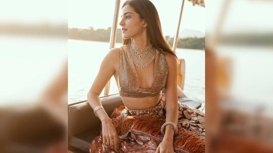 In this still, Ananya Panday gives a candid shot as she looks away into oblivion on a boat donning a rustic brown shimmery bralette, lehenga and a statement dupatta.(Instagram/@ananyapanday)
