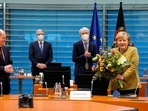 Acting German Chancellor Angela Merkel receives a bouquet from acting German Finance Minister Olaf Scholz prior to the weekly cabinet meeting at the Chancellery in Berlin, Germany.&nbsp;