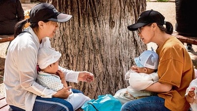 Two women sit on a bench with their babies in a park in Beijing. AFP