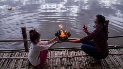 A mother and her daughter hold a Krathong, a floral arrangement with incense and candles, before setting it afloat in the Ping River during the Loy Krathong festival in Chiang Mai, Thailand. (Bloomberg)