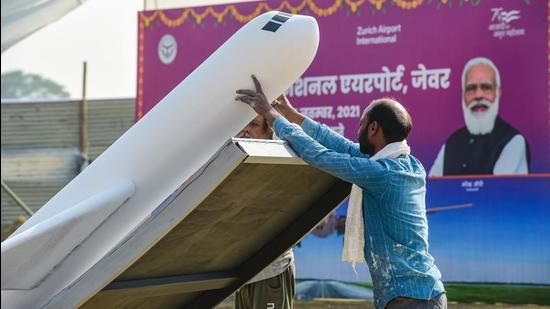 A worker installs a replica of an airplane as preparation are underway on the eve of the foundation stone laying ceremony of Jewar Airport by Prime Minister Narendra Modi.