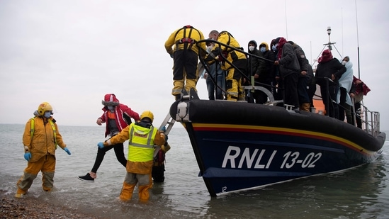 Migrants are helped ashore from a lifeboat at a beach in Dungeness, on the south-east coast of England.(AFP)