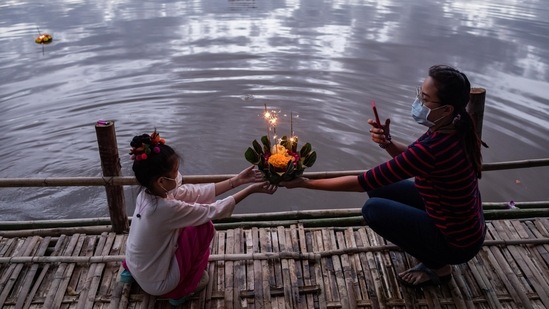 A mother and her daughter hold a Krathong, a floral arrangement with incense and candles, before setting it afloat in the Ping River during the Loy Krathong festival in Chiang Mai, Thailand.(Bloomberg)