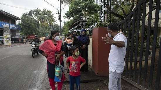 A school staff gestures to parents waiting outside the gate to maintain social distancing as a precaution against Covid-19, as schools reopened in Kochi, on November 1. In October, 70% of the deaths recorded in the state were backlog deaths. (AP)