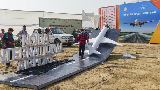 Workers install a replica of an airplane as preparation are underway for the foundation stone laying ceremony of Noida International Airport in Jewar by Prime Minister Narendra Modi, on Wednesday.(PTI Photo)