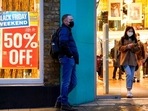 A person wears a mask as he stands close to a Black Friday sign in Covent Garden, in London.(AP) A person wears a mask as he stands close to a Black Friday sign in Covent Garden, in London.(AP)