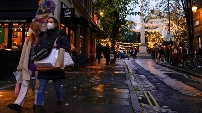 Shoppers carry bags as they wear face masks in the area of Covent Garden, in London. (AP)