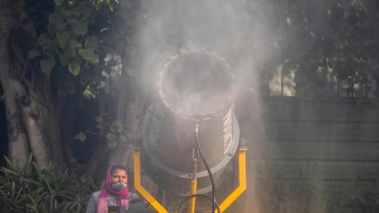 A municipal worker operates a mist machine beside a street amid smoggy conditions in New Delhi.(AFP)