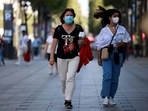 People wearing protective face masks walk on the Champs Elysees Avenue in Paris.