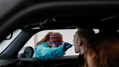 A woman takes a saliva sample of a man at a drive through rapid coronavirus disease (Covid-19) test centre amid the pandemic in Furstenfeldbruck, Germany. (REUTERS)