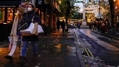 Shoppers carry bags as they wear face masks in the area of Covent Garden, in London. (AP)