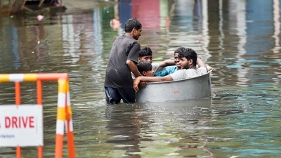 Young men sit in a tub as another man pushes them on a waterlogged street following heavy rain in Chennai, Saturday. (PTI) Young men sit in a tub as another man pushes them on a waterlogged street following heavy rain in Chennai, Saturday. (PTI)