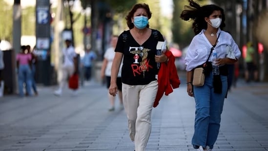 People wearing protective face masks walk on the Champs Elysees Avenue in Paris.(Representative Photo/Reuters)