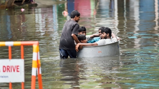 Young men sit in a tub as another man pushes them on a waterlogged street following heavy rain in Chennai, Saturday. (PTI)