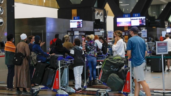Travelers queue at a check-in counter at OR Tambo International Airport in Johannesburg on November 27, 2021, after several countries banned flights from South Africa following the discovery of a new Covid-19 variant Omicron. (Photo by Phill Magakoe / AFP) Travelers queue at a check-in counter at OR Tambo International Airport in Johannesburg on November 27, 2021, after several countries banned flights from South Africa following the discovery of a new Covid-19 variant Omicron. (Photo by Phill Magakoe / AFP)