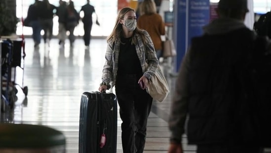 A traveller wears a face covering while heading to the American Airlines check-in counter.(AP Photo/David Zalubowski)