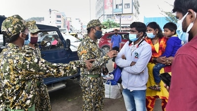 A civic body marshal asks citizens to wear masks at a crowded market in Bengaluru on Sunday. (PTI) A civic body marshal asks citizens to wear masks at a crowded market in Bengaluru on Sunday. (PTI)