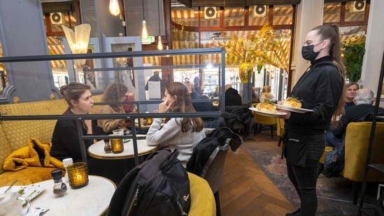 A waitress attends guests during lunch at Brasserie De Joffers in Amsterdam, on November 28, 2021.(AFP) A waitress attends guests during lunch at Brasserie De Joffers in Amsterdam, on November 28, 2021.(AFP)
