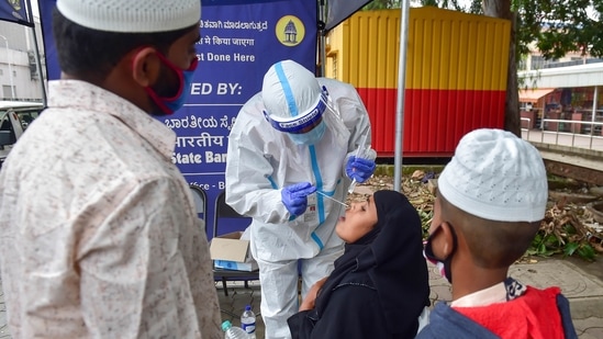 A medic collects sample from a passenger for COVID-19 test, at KSRTC bus stand in Bengaluru on Sunday.(PTI Photo)