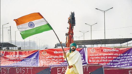 A farmer waves the Indian tri-colour at Ghazipur protest site after a bill to repeal the farm laws was passed in Parliament on Monday. (Sakib Ali/HT photo)