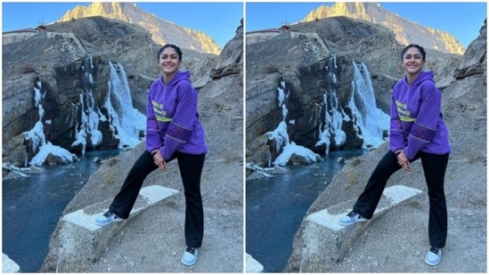 Mrunal posed on a rock of sorts, with a picturesque backdrop of a flowing stream and snow.(Instagram/@mrunalthakur)