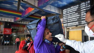 A healthcare worker collects a swab sample of a commuter for the Covid-19 test at New Delhi Railway station on Tuesday. (ANI) A healthcare worker collects a swab sample of a commuter for the Covid-19 test at New Delhi Railway station on Tuesday. (ANI)