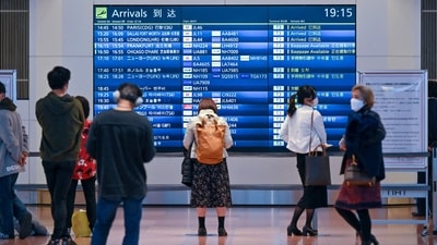 People stand in front of an arrivals board at Tokyo's Haneda international airport on December 1, 2021, as Japan suspended all new flight bookings into the country in response to the Omicron Covid variant (Photo by Kazuhiro NOGI / AFP) People stand in front of an arrivals board at Tokyo's Haneda international airport on December 1, 2021, as Japan suspended all new flight bookings into the country in response to the Omicron Covid variant (Photo by Kazuhiro NOGI / AFP)