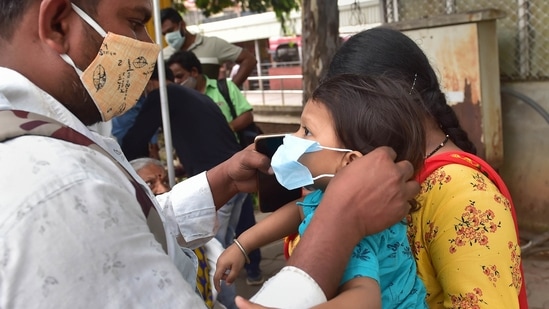A man helps his son to wear mask at Covid-19 test centre at KSRTC bus stand in Bengaluru.(PTI)
