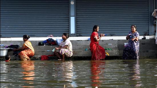 Women wash clothes on a waterlogged street in Chennai on Wednesday. (PTI)