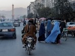 A group of women wearing burqas crosses the street as members of the Taliban drive past in Kabul, Afghanistan.&nbsp;