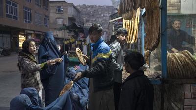 A man disributes bread to Burka-wearing Afghan women outside a bakery in Kabul, Afghanistan, on Thursday. (AP) A man disributes bread to Burka-wearing Afghan women outside a bakery in Kabul, Afghanistan, on Thursday. (AP)
