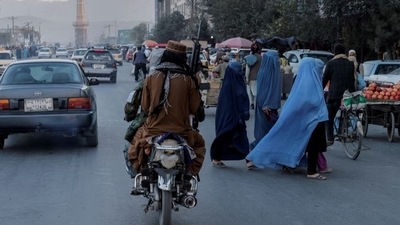 A group of women wearing burqas crosses the street as members of the Taliban drive past in Kabul, Afghanistan.&nbsp; (Reuters File Photo)