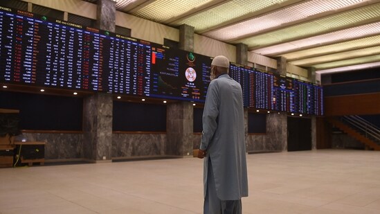A stockbroker looks at share prices on an index board during a trading session at the Pakistan Stock Exchange (PSX) in Karachi on December 2, 2021. (Photo by Rizwan TABASSUM / AFP)