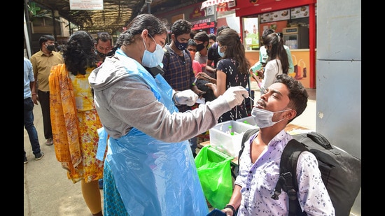 A health worker conducts COVID-19 testing of commuters amid fear of spread of a new variant of COVID-19, in Bengaluru. (PTI)