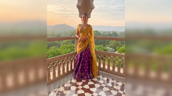 Esha Gupta redefines elegance and royalty as she poses in an embellished yellow and purple lehenga from a fort in Jaipur.(Instagram/@egupta)