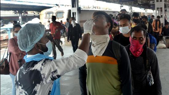 A healthcare worker collects swab samples for Covid-19 of passengers arriving on outstation trains, at Lokmanya Tilak Terminal. (HT PHOTO)