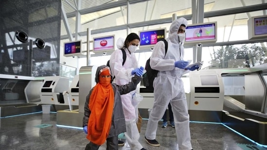 An Indian family dressed in personnel protective suits walk towards security gates after checking in their baggage at Kempegowda International Airport in Bengaluru, India.(AP)