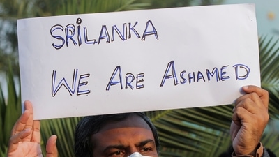A man along with others carries a sign, condemning the lynching of the Sri Lankan manager of a garment factory after an attack on the factory in Sialkot, during a protest in Lahore. (Reuters)