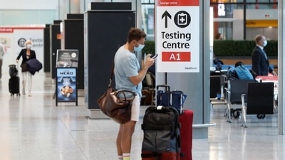 A passenger stands next to a Covid-19 testing centre sign in the International arrivals area of Terminal 5 in London's Heathrow Airport, Britain. (Reuters)