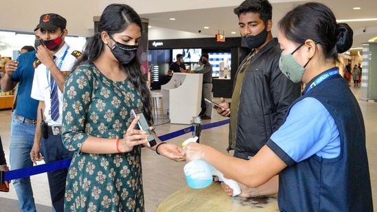 A security personnel santises the hands of a visitor as she checks the Covid-19 vaccination certificate at the entrance of a mall.(PTI)
