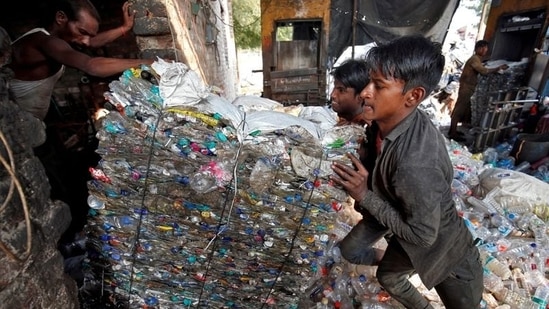 Workers push a bundle of crushed plastic bottles at a recycling factory in Ahmedabad, India.(REUTERS File)