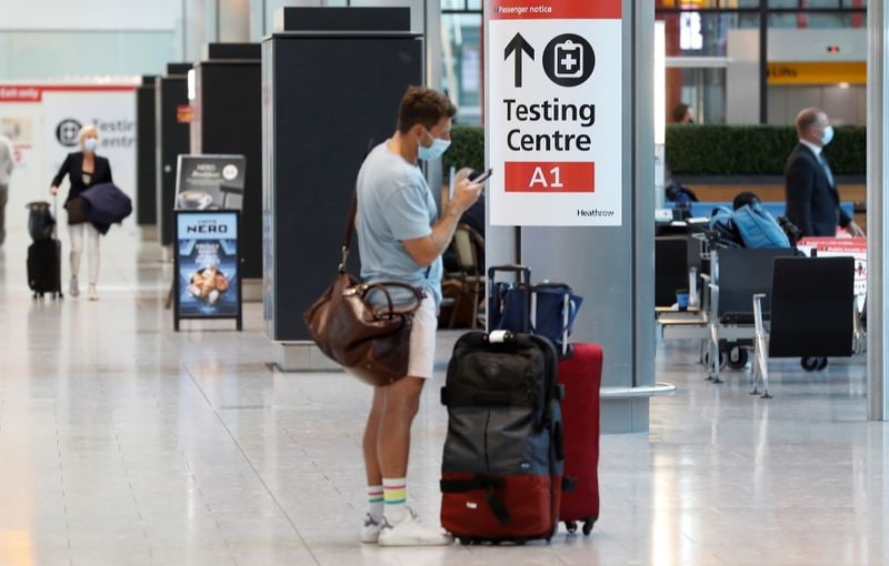 A passenger stands next to a Covid-19 testing centre sign in the International arrivals area of Terminal 5 in London's Heathrow Airport. (Reuters)