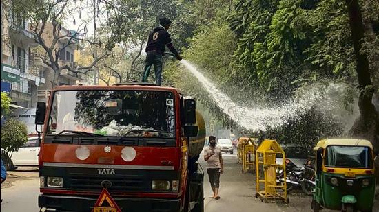 A municipal worker sprays water on roadside trees as part of efforts to reduce air pollution in New Delhi. (AP/File)