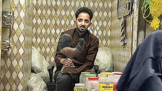Shariq instantly stretches his arm towards an upper shelf. The next moment, he is holding the rooster, coated in dust, which wafts towards the street like slow-moving winter mist.