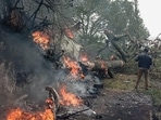 A man stands next to the burning debris of an IAF Mi-17V5 helicopter crash site in Coonoor, Tamil Nadu, on Wednesday.&nbsp;