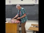 The image shows the teacher opening the Christmas gift by the students.